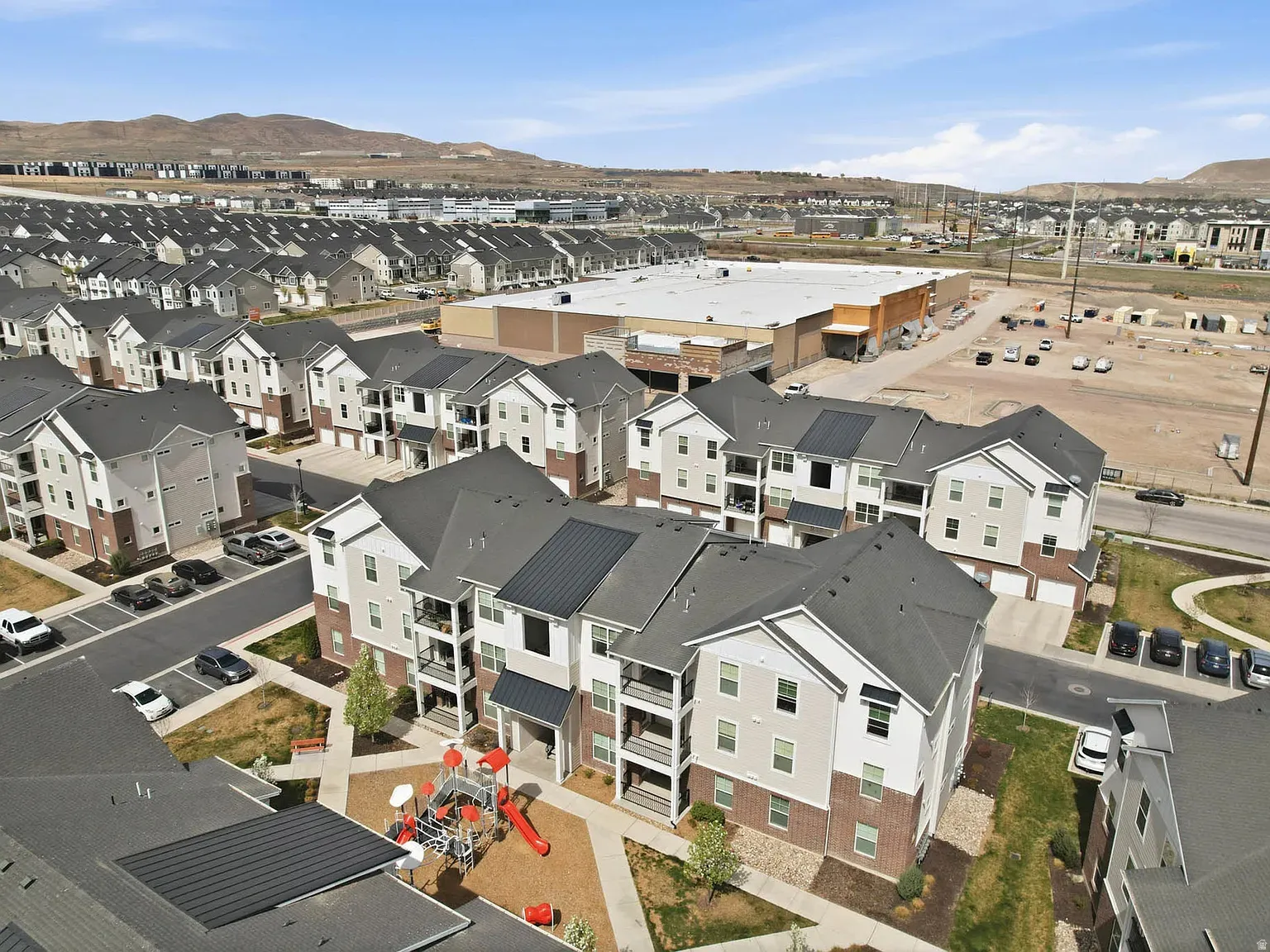 Modern multi-story buildings featuring balconies, attached garages, and a communal playground