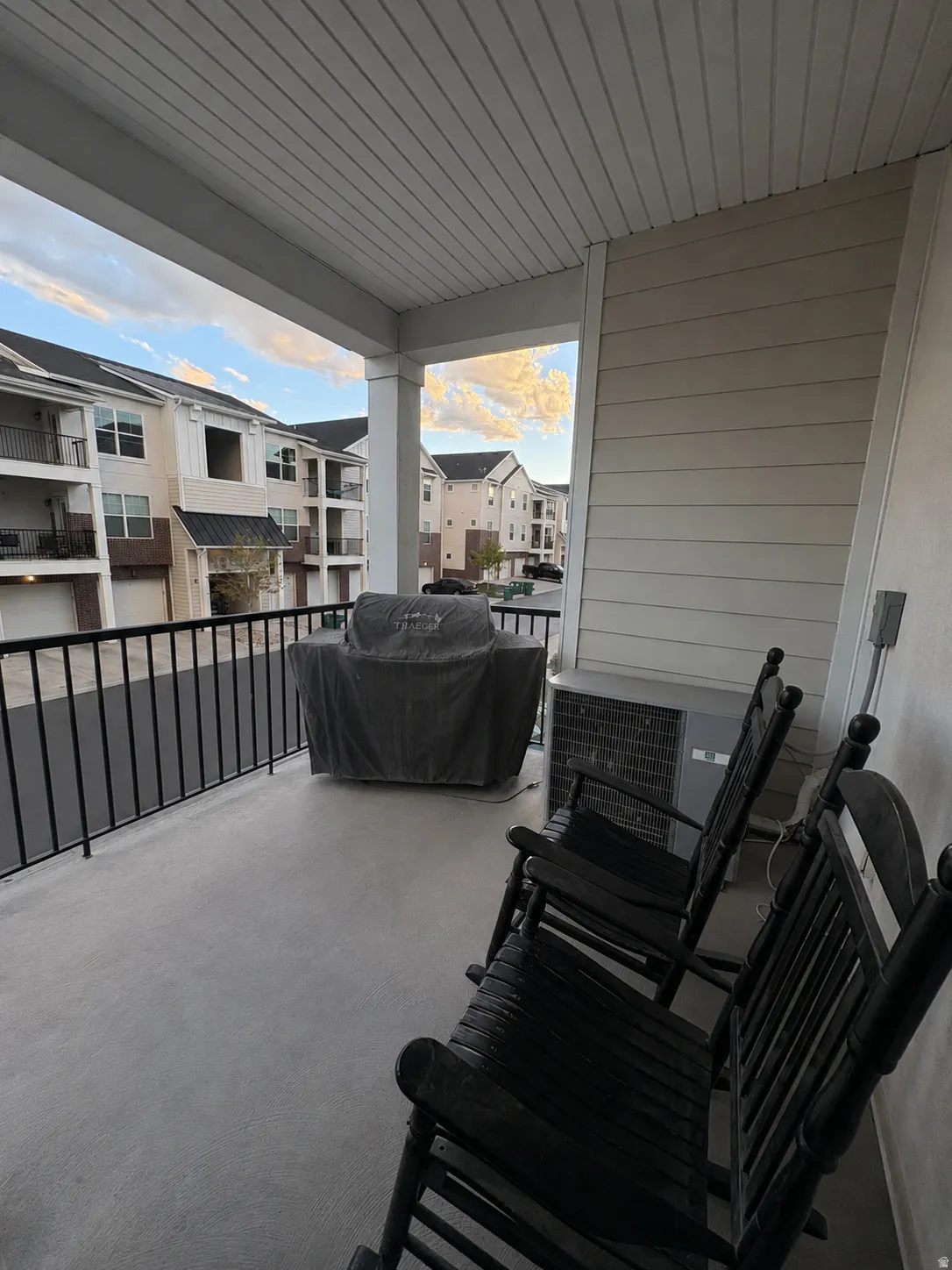 Covered outdoor patio with a plank ceiling, light-toned siding, and a black metal railing