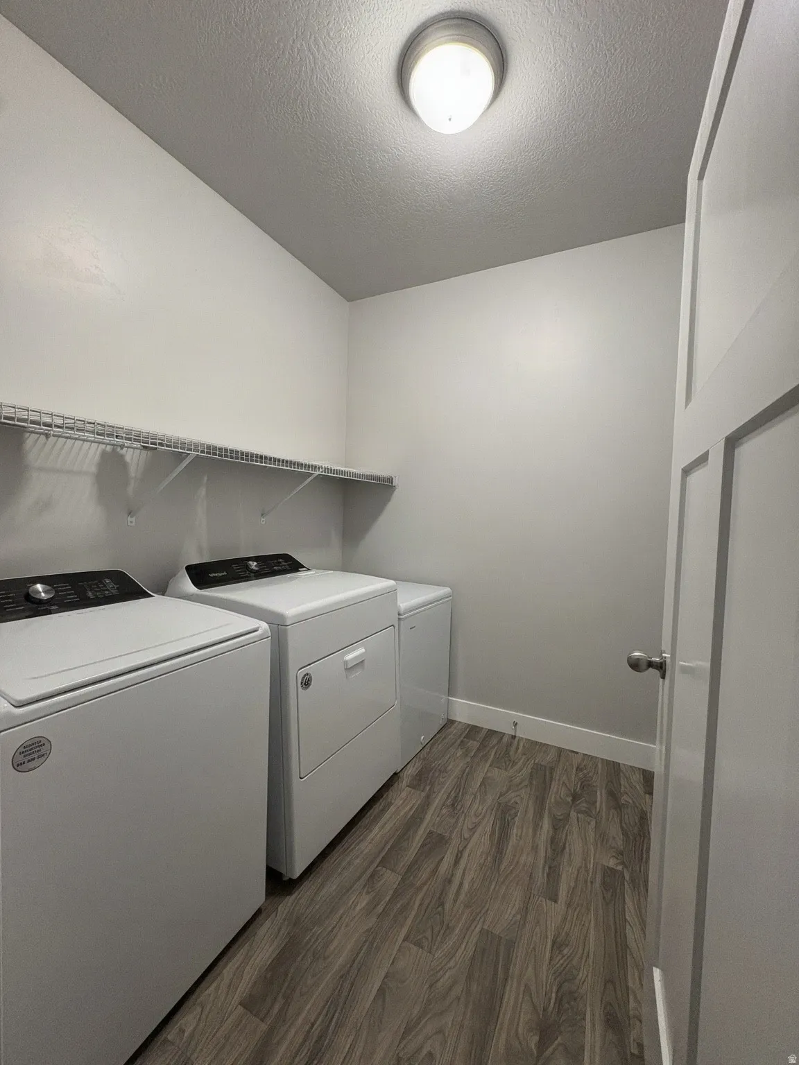 Wood-finish flooring, overhead wire shelving, and a flush-mount ceiling light fixture
