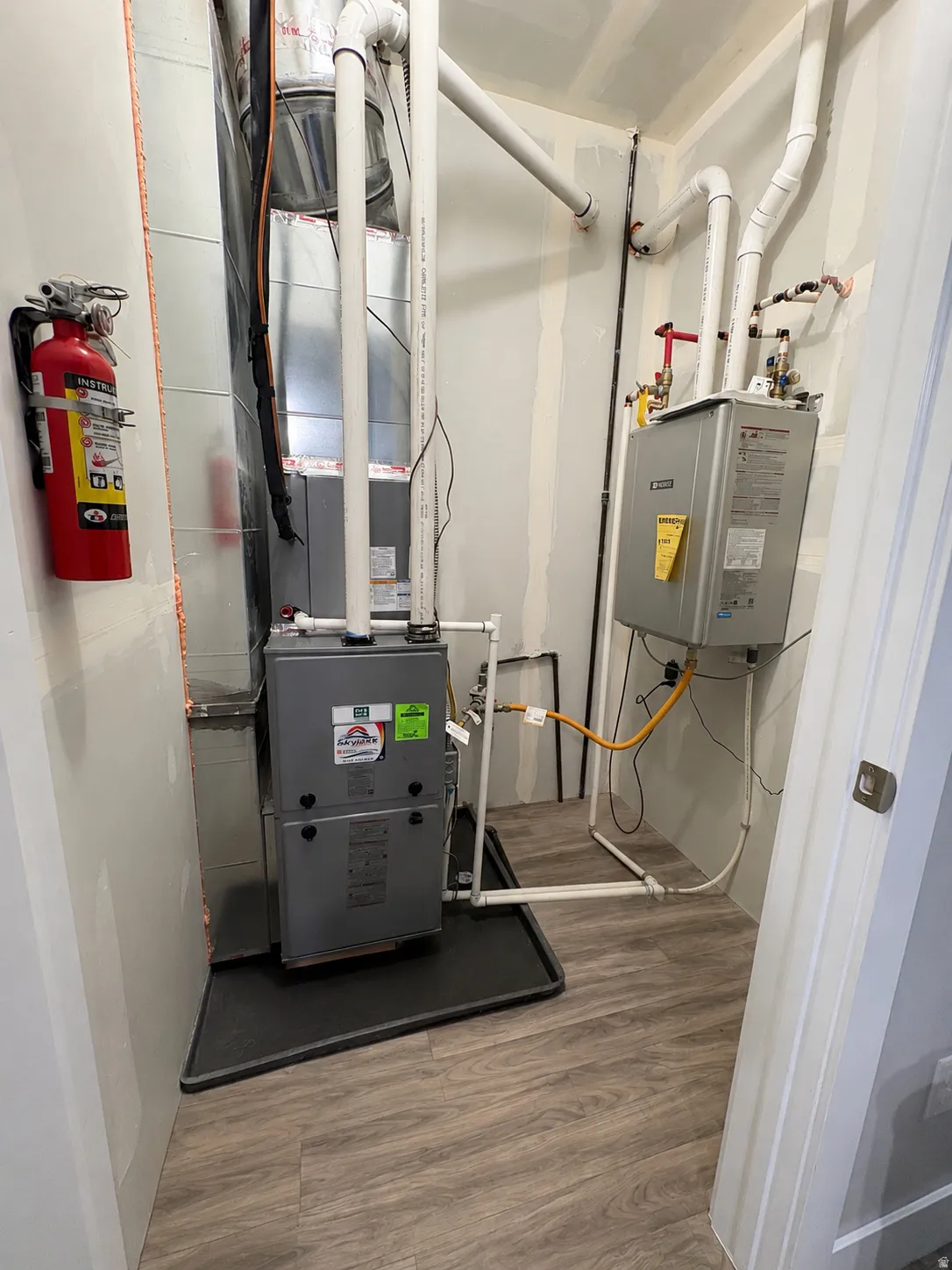 Wood-finish flooring with a utility area, featuring a furnace and a water heater