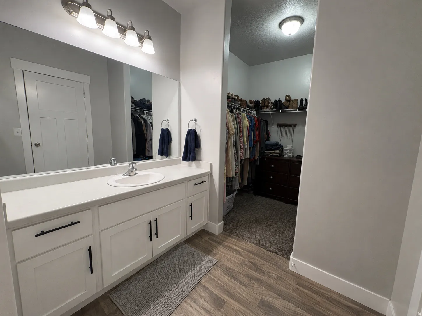 White vanity with matte black hardware, single undermount sink, and light-colored countertop