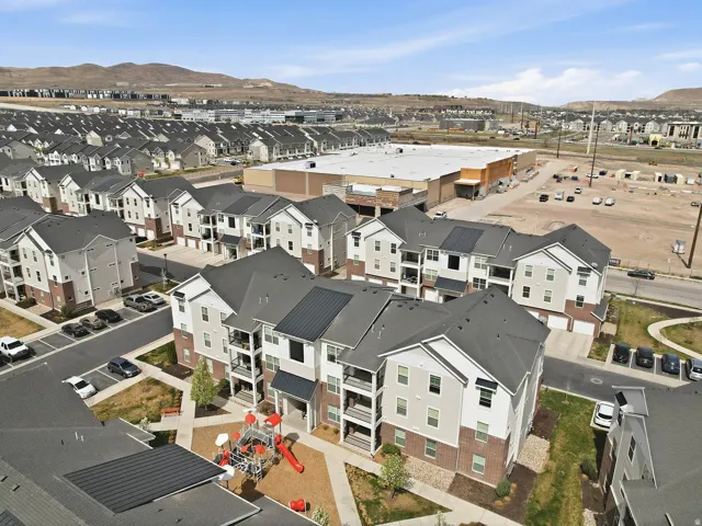 Modern multi-story buildings featuring balconies, attached garages, and a communal playground
