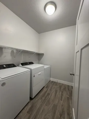 Wood-finish flooring, overhead wire shelving, and a flush-mount ceiling light fixture