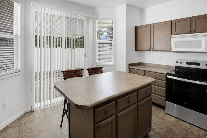 Kitchen featuring an island, integrated range and microwave, wood-finish cabinetry, and tiled flooring