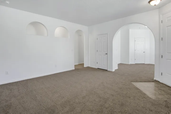 Arched wall niches and doorways with neutral carpeting throughout