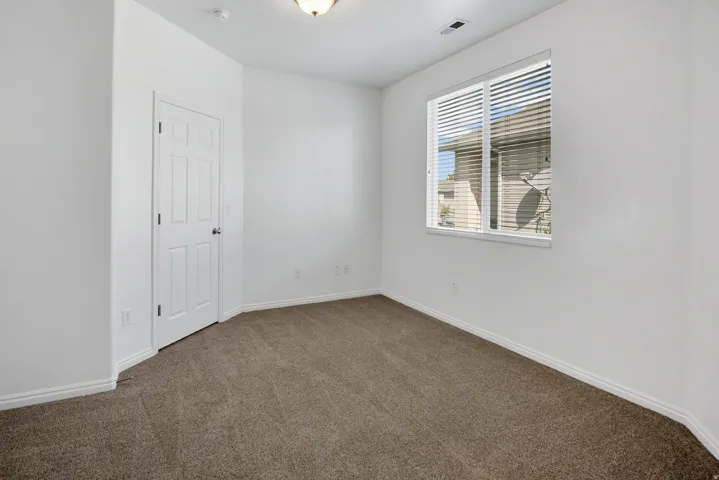 Neutral wall paint, plush carpet flooring, white trim, recessed lighting, and a white window frame with blinds