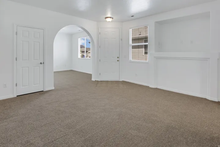 Expansive carpeting throughout with a built-in display niche, arched doorway, and white paneled doors