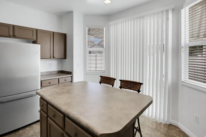 Kitchen island with countertop seating, stainless steel refrigerator, and recessed lighting