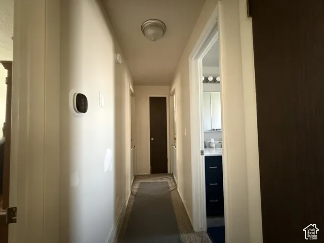 Hallway featuring a wall-mounted thermostat and a flush-mount ceiling light fixture