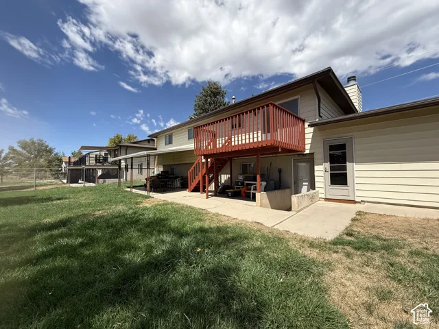 Rear exterior with a wood deck, concrete patio, and a sloped concrete path