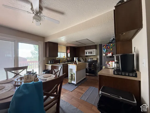 Wood-finish flooring, dark wood cabinetry, and a ceiling fan with integrated lighting