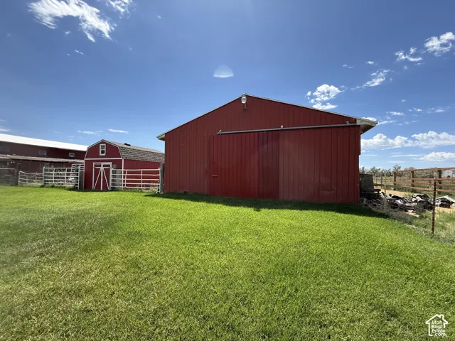 Expansive green lawn with red outbuildings, a red barn with a sliding door, and white fencing