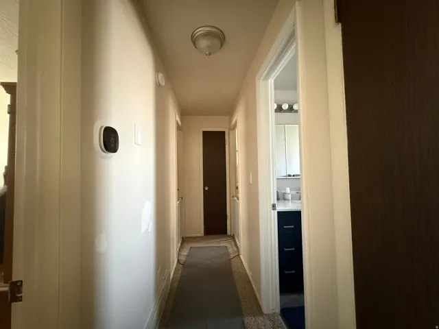 Hallway featuring a wall-mounted thermostat and a flush-mount ceiling light fixture