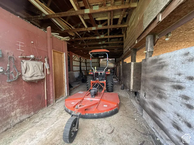 Wood-frame barn interior featuring exposed rafters, wood slat walls, and a dirt floor