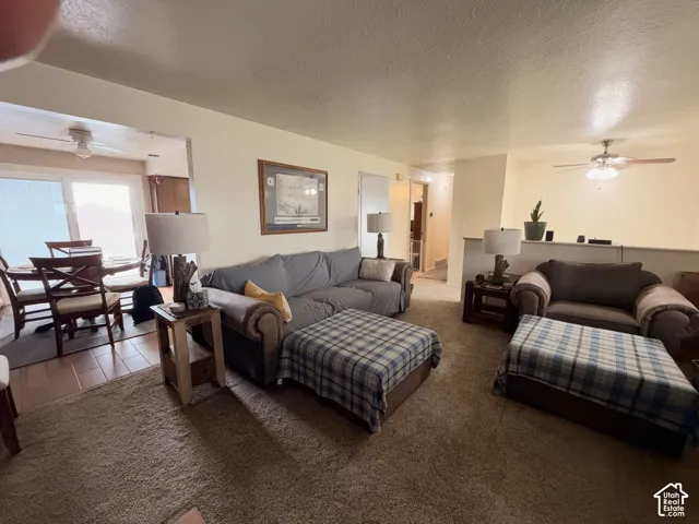 Living area featuring neutral wall tones, two ceiling fans with integrated lighting, and tile flooring in the dining area
