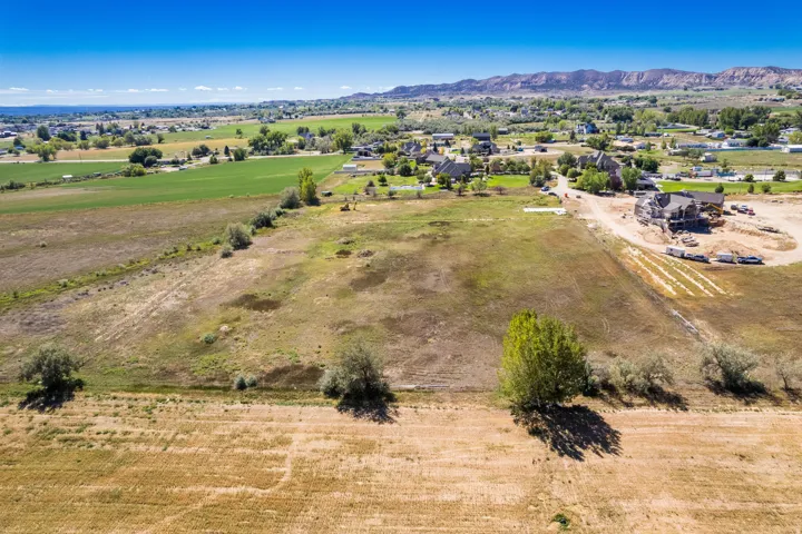 Expansive undeveloped land featuring a clear blue sky, distant mountainous terrain, and scattered natural foliage