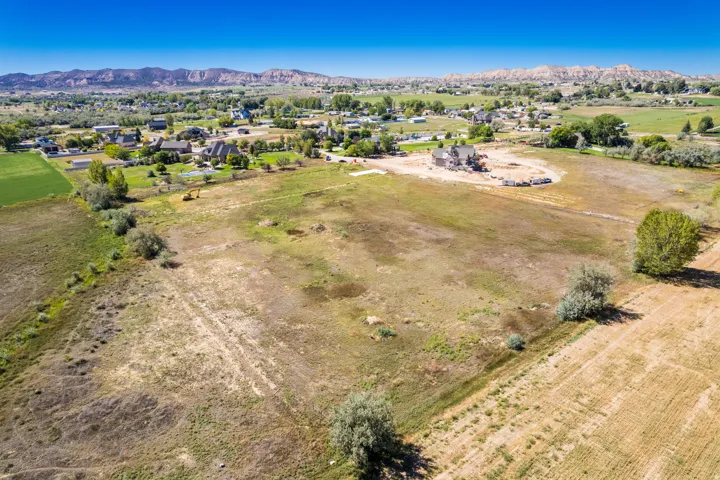 Expansive open land with distant mountain backdrop, surrounded by established residential properties and natural landscaping