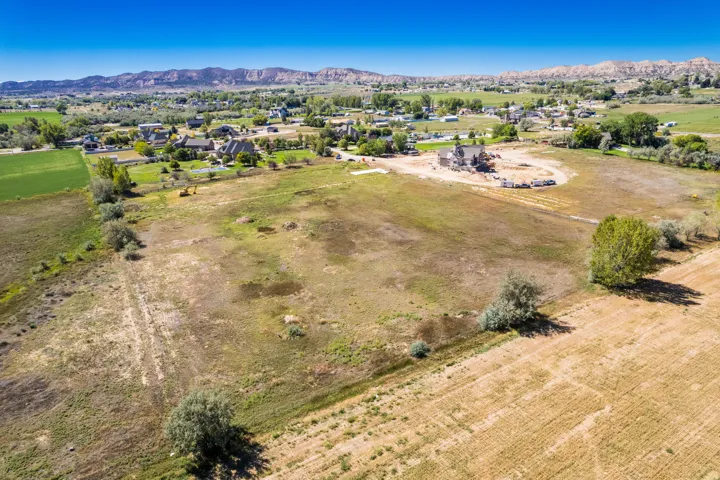 Expansive undeveloped land with distant mountainous terrain, a clear blue sky, and scattered mature trees