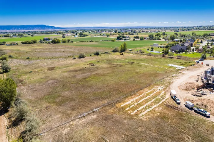 Expansive rural landscape with distant mountains and scattered residential properties, featuring undeveloped land