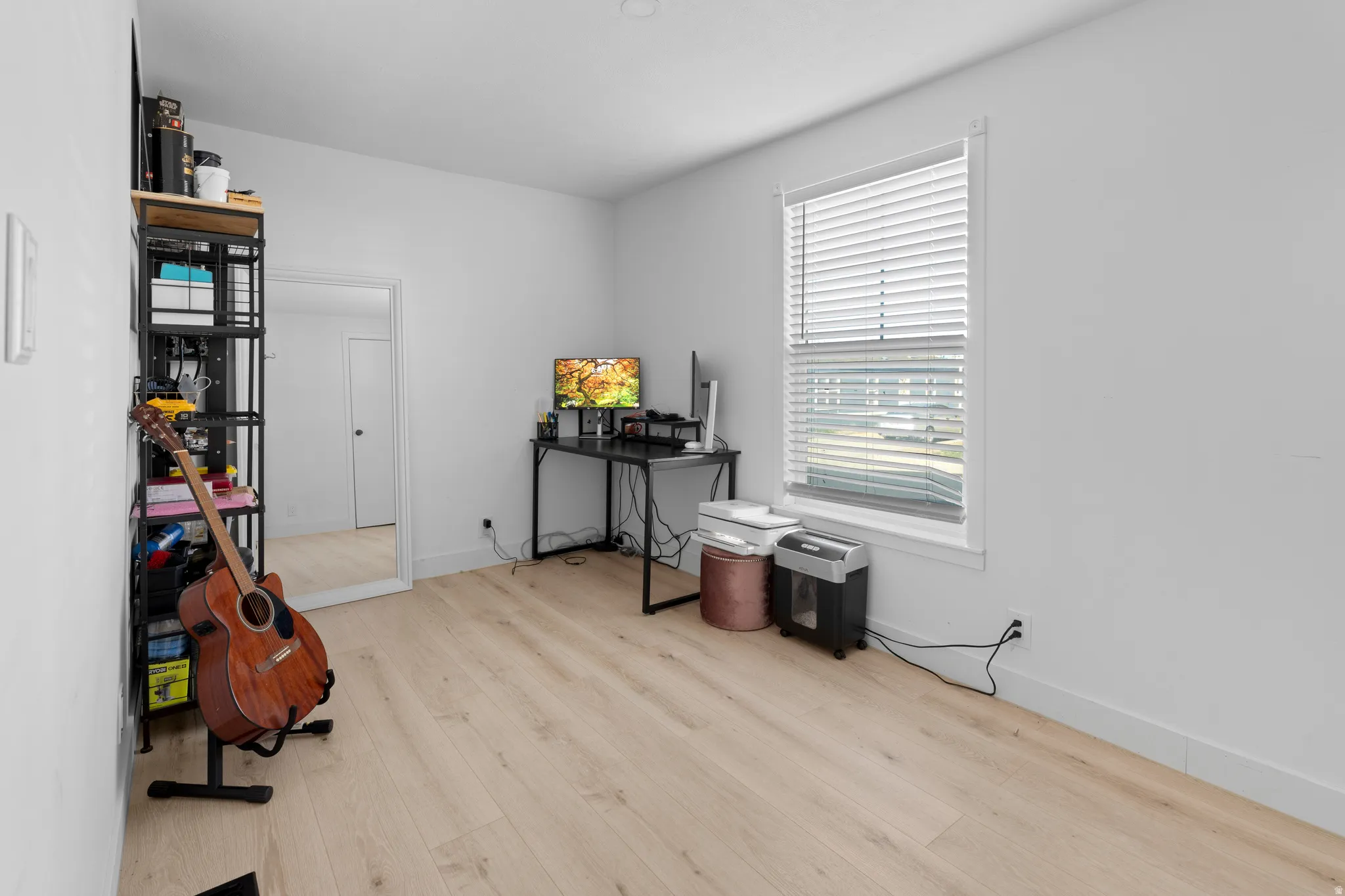 Light wood-finish flooring, white walls, and a window with blinds