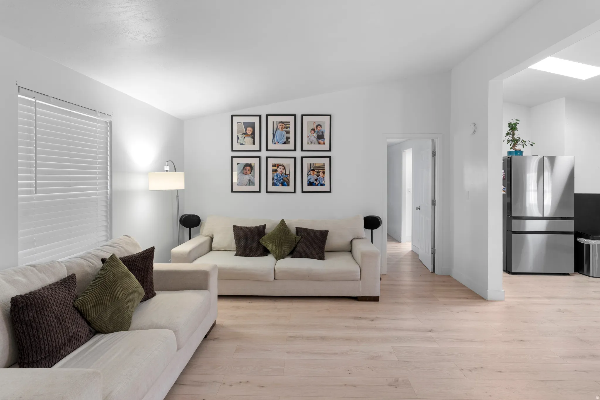 Bright living area featuring wood-finish flooring, white walls, and a window with horizontal blinds