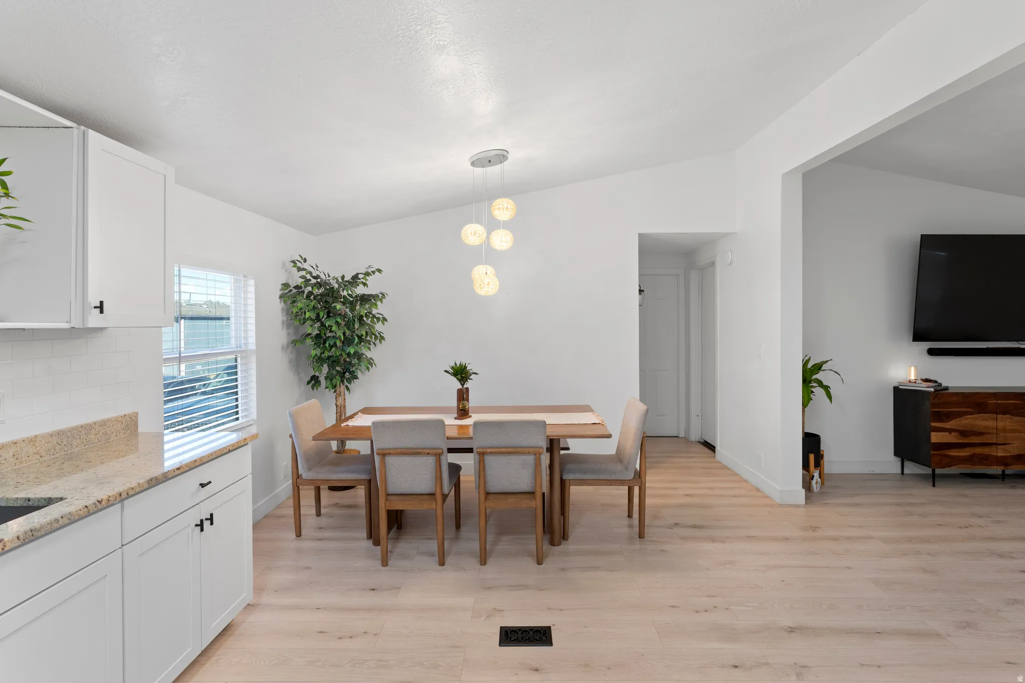 Open-concept dining area with vaulted ceilings, wood-finish flooring, and a contemporary chandelier
