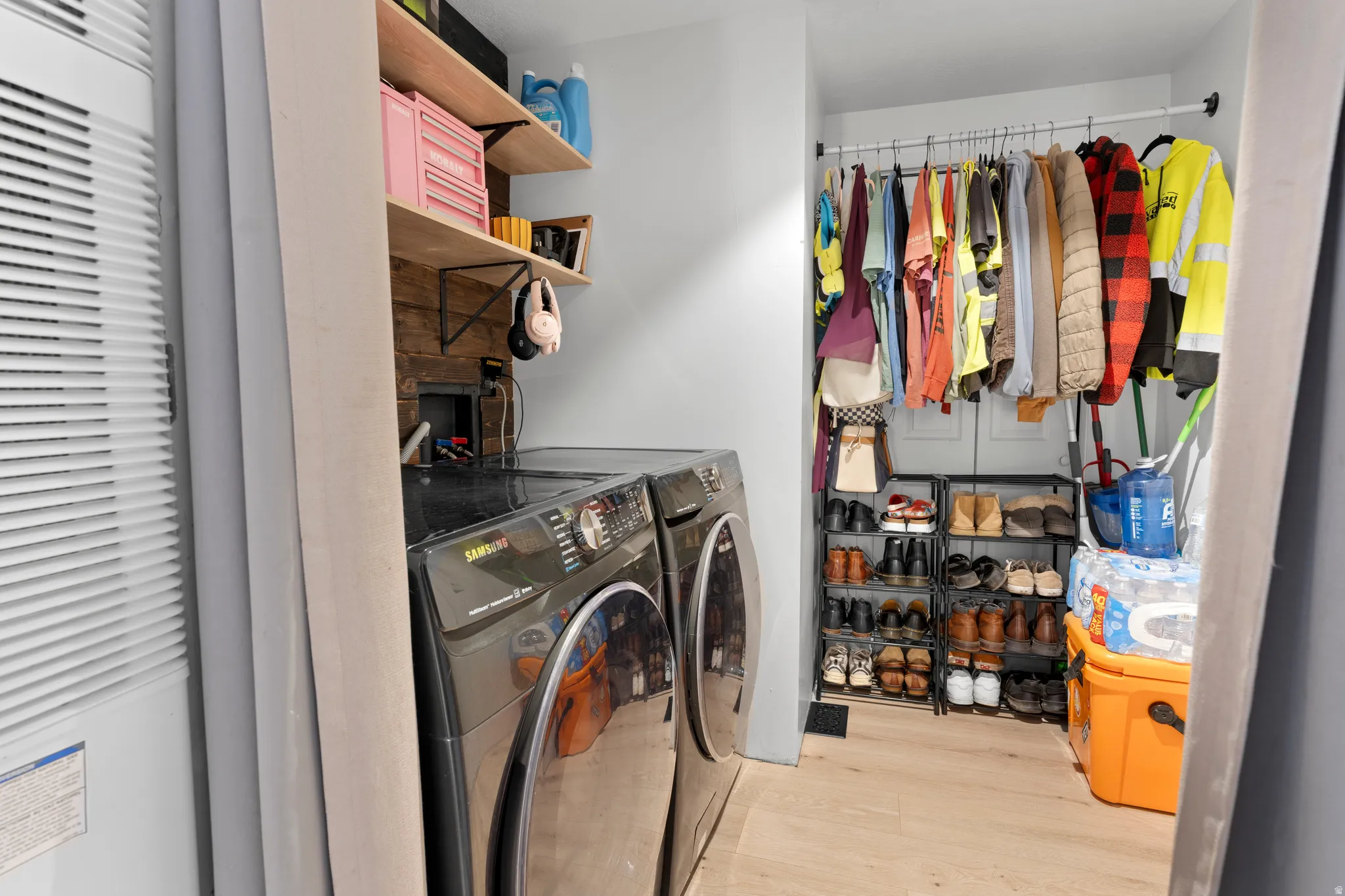 Laundry area with front-loading appliances, wood-finish flooring, and open shelving
