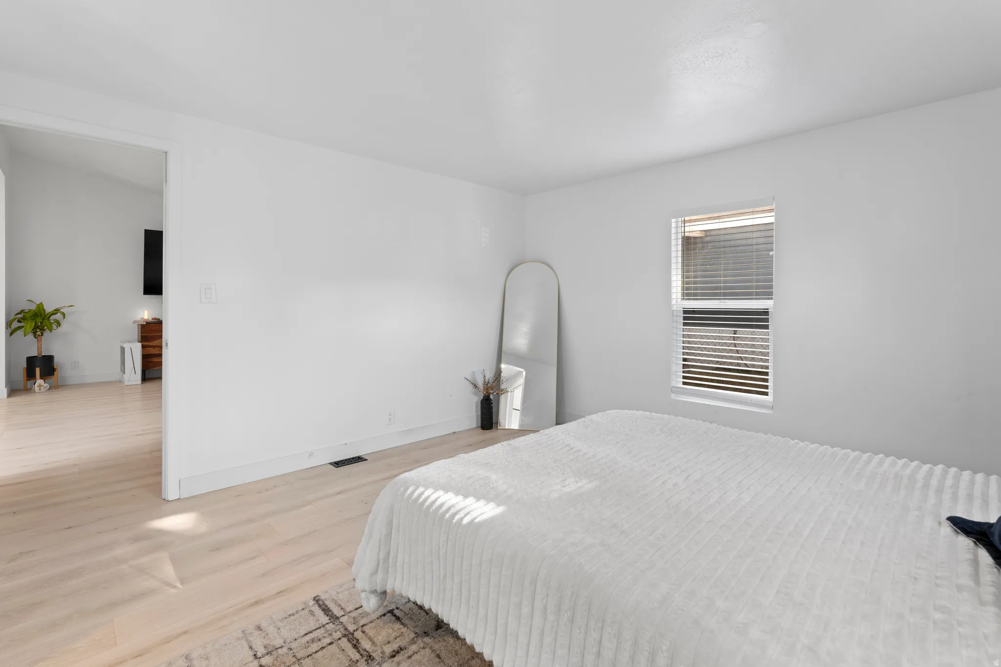 Bright room featuring a window with horizontal blinds, light-toned wood-finish flooring, and a neutral color palette throughout