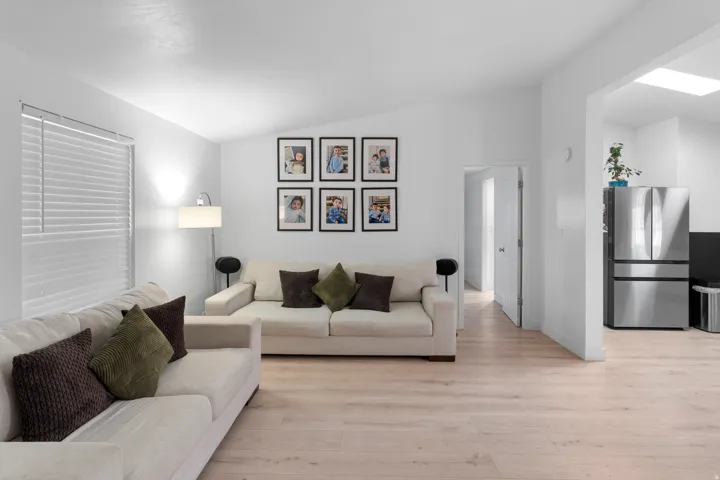 Bright living area featuring wood-finish flooring, white walls, and a window with horizontal blinds