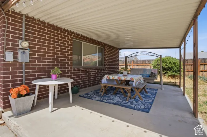 Covered patio featuring a concrete floor, brick exterior, and a privacy fence