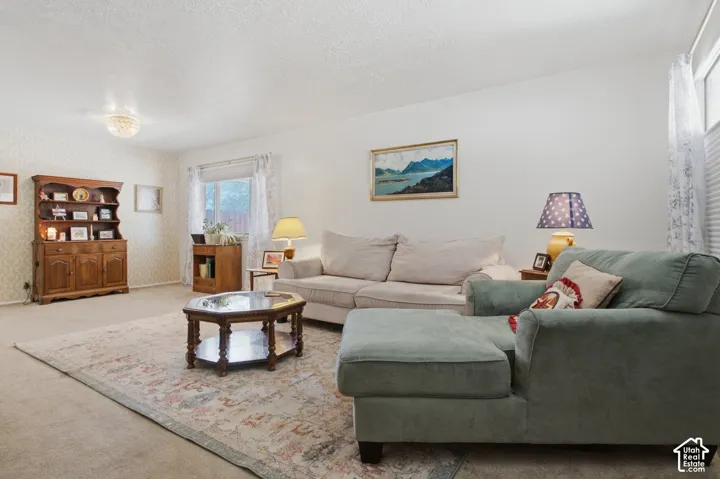 Recessed lighting, wall-to-wall carpeting, and a window with blinds and sheer curtains