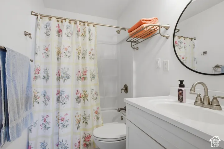 Bathroom featuring a white vanity with an integrated sink, brushed nickel faucet, a rounded mirror, and a shower-over-tub combination