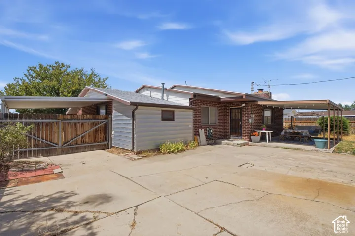 Brick exterior with a covered patio, attached carport, and a detached storage shed