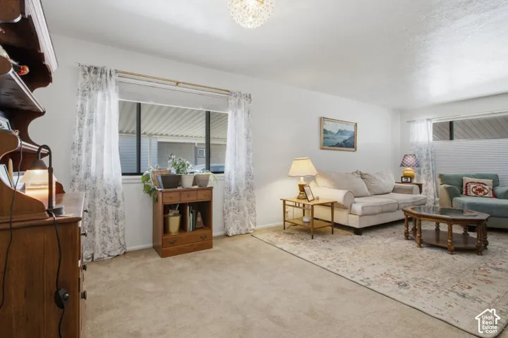 Carpeted living space with a large window, a second smaller window, and a decorative overhead light fixture