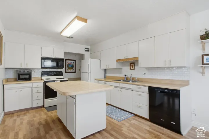 Kitchen featuring white cabinetry, wood-finish flooring, light wood-finish countertops, subway tile backsplash, and a central island