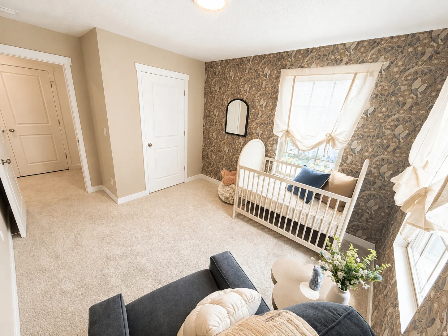Carpeted flooring, textured accent wall, two panel interior doors, and a window with tie-up shades