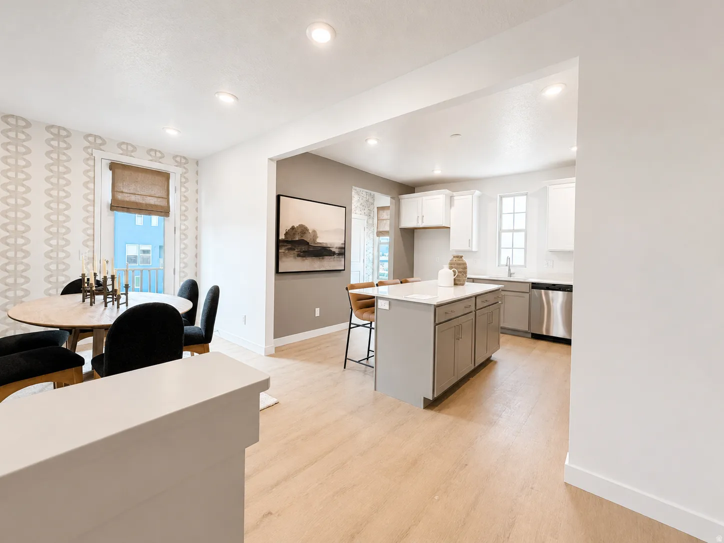 Recessed lighting, wood-finish flooring, kitchen island with seating, stainless steel appliances, and white cabinetry