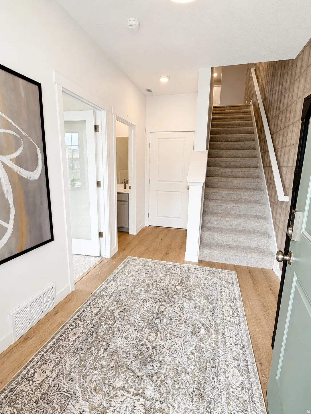 Wood-finish flooring throughout the entry with recessed ceiling lighting