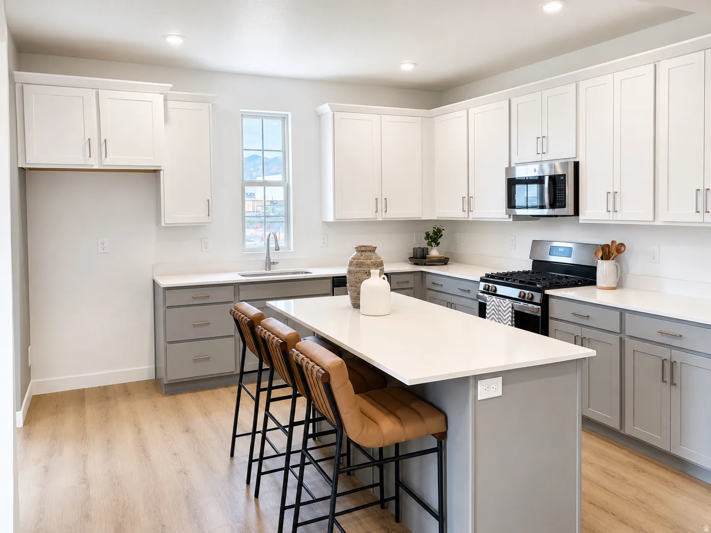 Kitchen featuring a center island, wood-finish flooring, recessed lighting, white upper cabinetry, and a stainless steel appliance suite