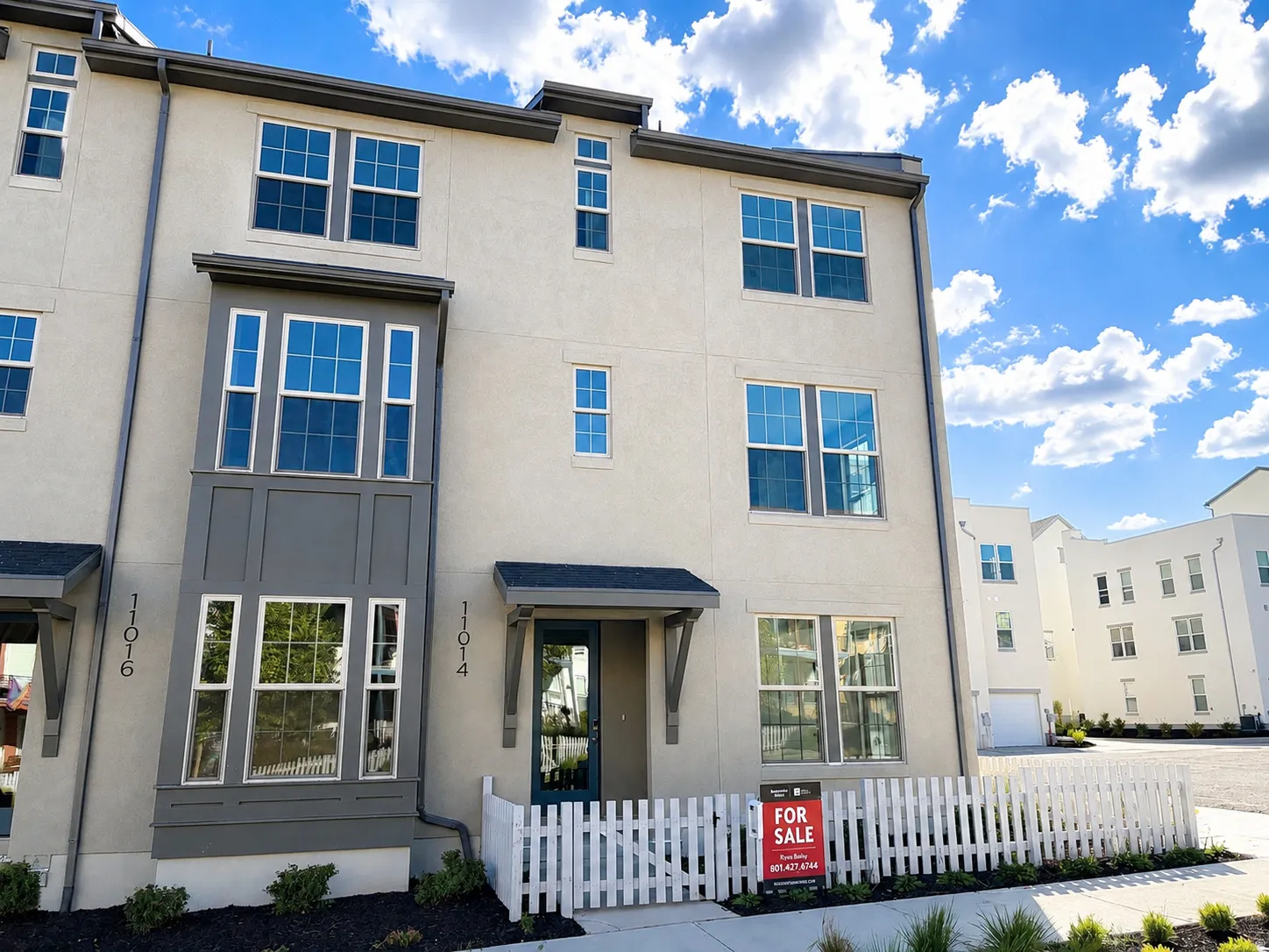 Three-story townhome featuring a stucco exterior and multi-pane windows