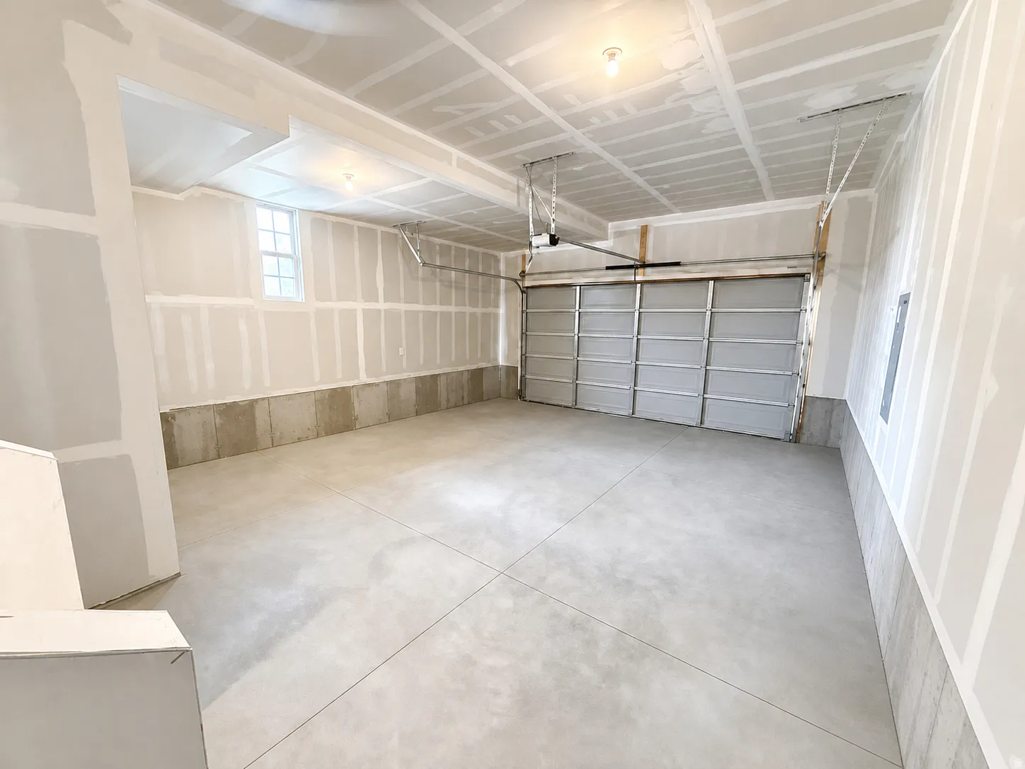 Attached garage with a concrete floor, exposed drywall walls, and a window