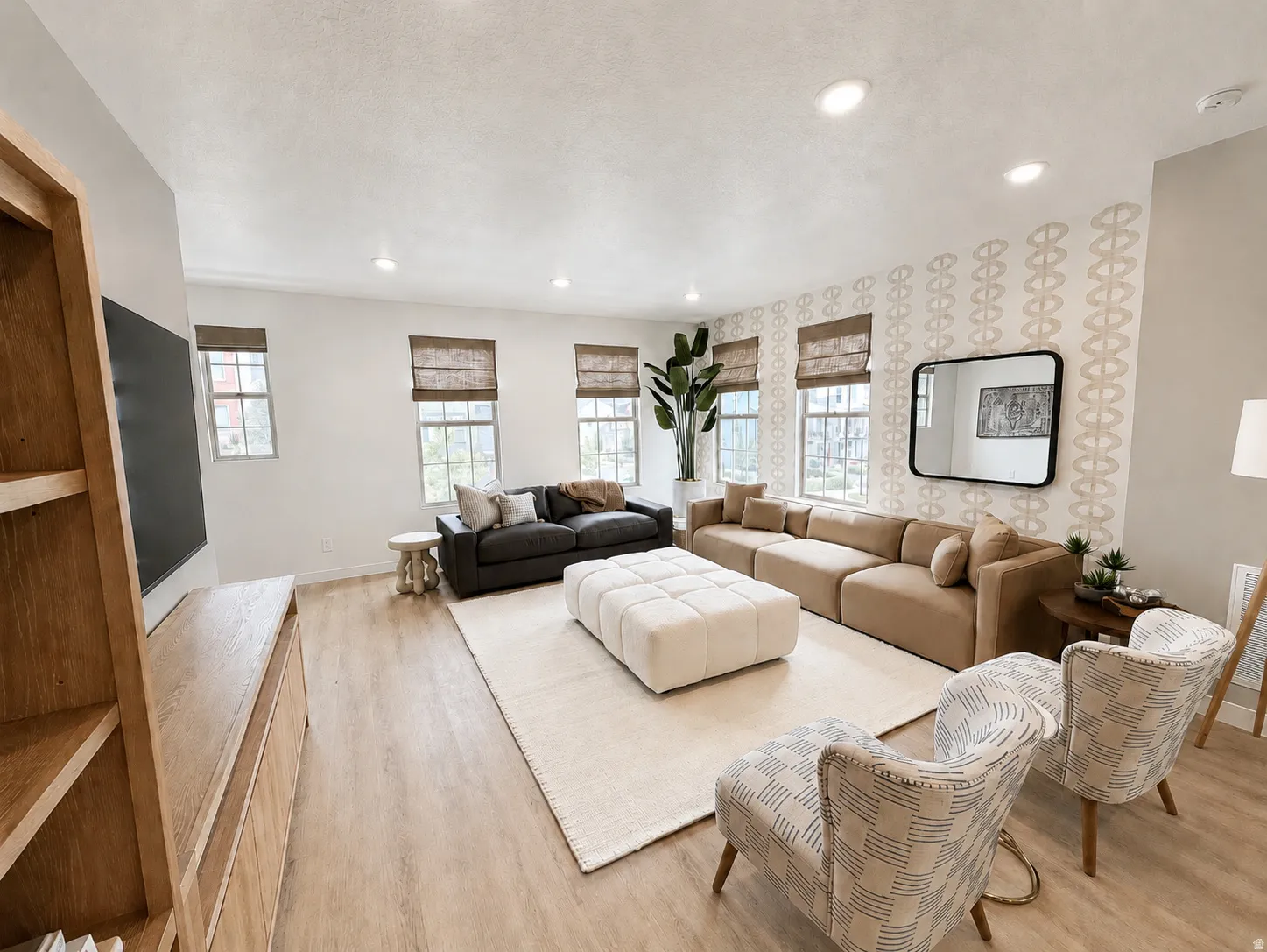 Spacious living area featuring wood-finish flooring, recessed lighting, multiple windows with blinds, and a built-in wooden media console with shelving