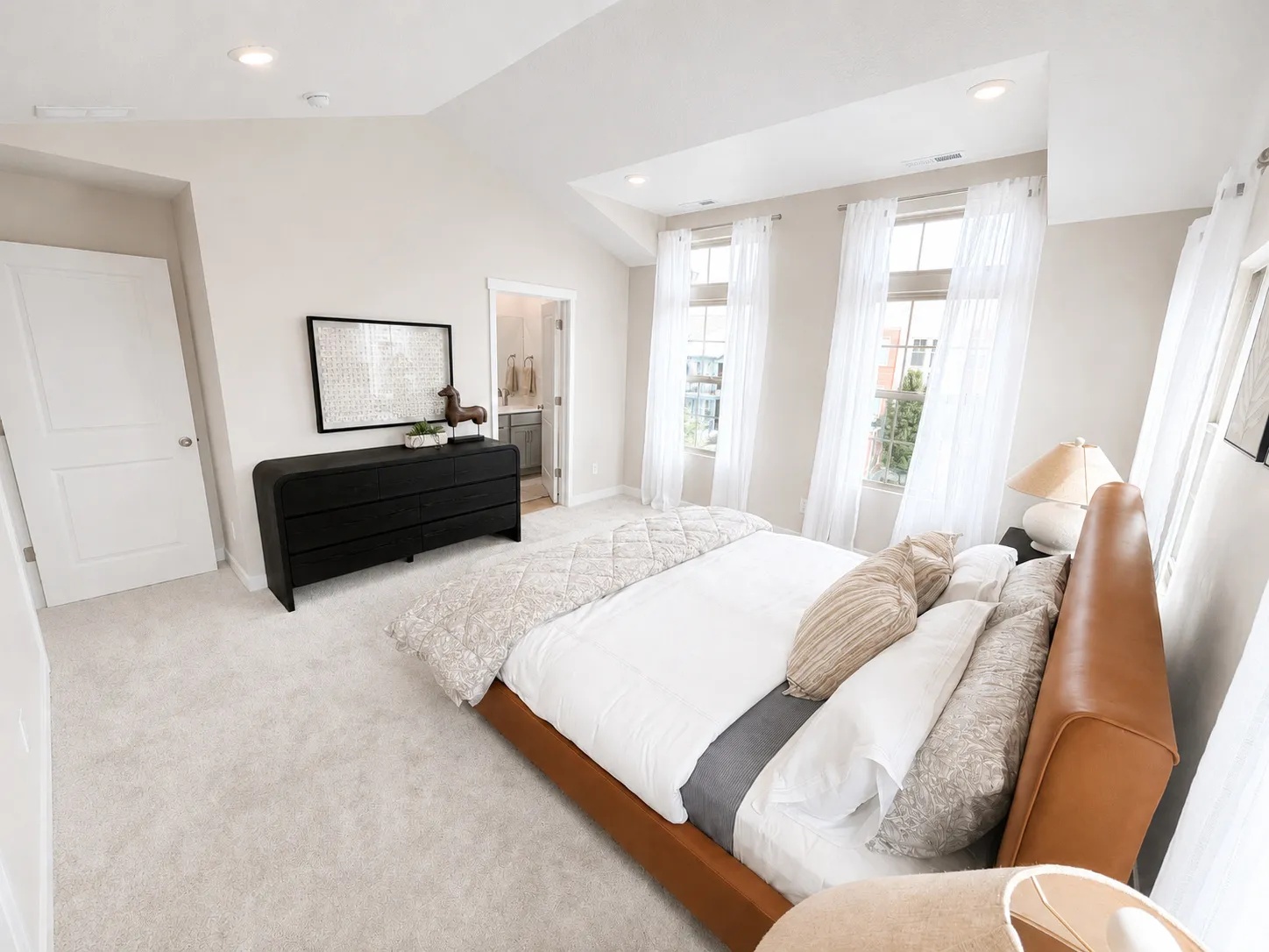 Vaulted ceiling with recessed lighting, light-toned carpet flooring, two-panel interior doors, and multiple windows