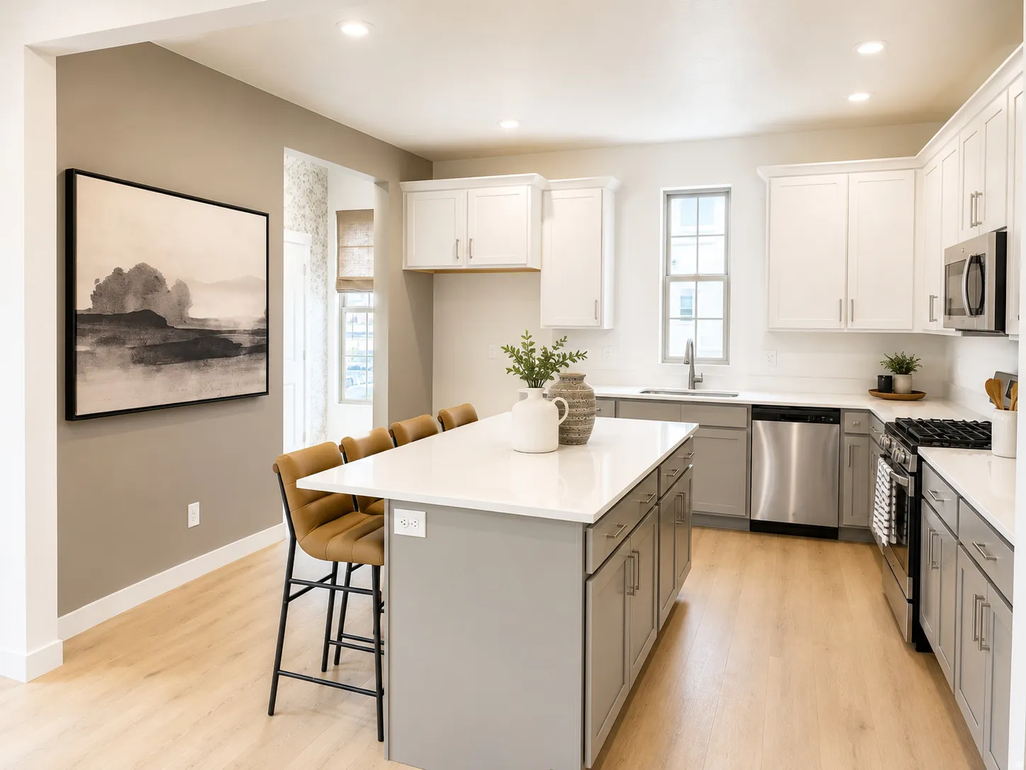 Modern kitchen featuring a large island with a light-colored countertop, light wood-finish flooring, two-tone cabinetry, stainless steel appliances, and recessed lighting