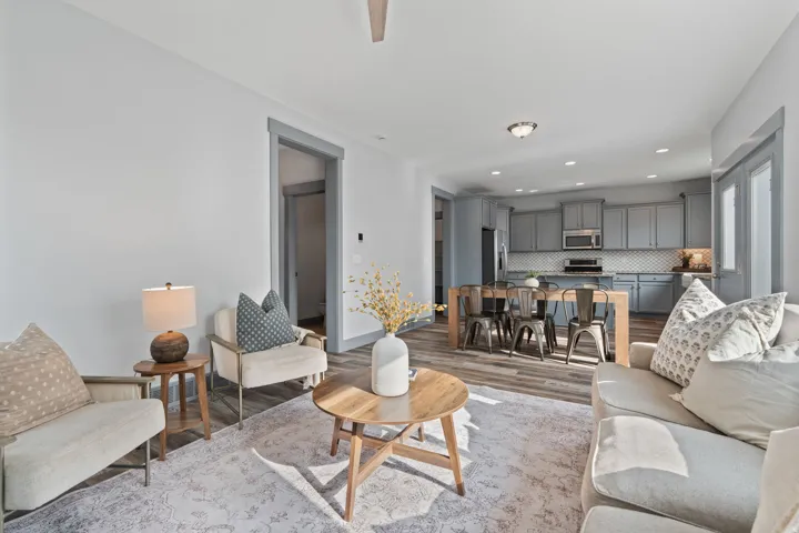 Open-concept living area featuring wood-finish flooring, recessed lighting, and a modern kitchen with gray cabinetry and a tiled backsplash