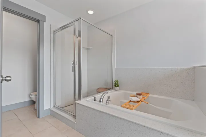 Built-in soaking tub with surrounding speckled solid surface, glass-enclosed shower, and recessed lighting