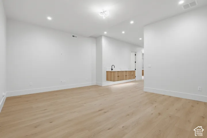 Open floor plan featuring wood-finish flooring, recessed lighting, and a wall-mounted light fixture