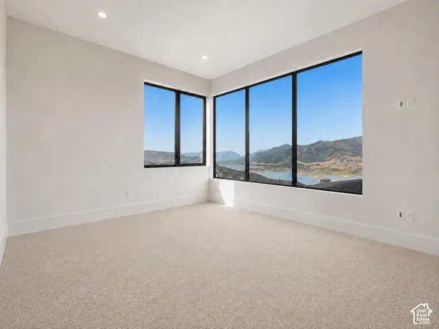 Recessed lighting, large picture windows, light-colored carpeting, white walls, and broad baseboards