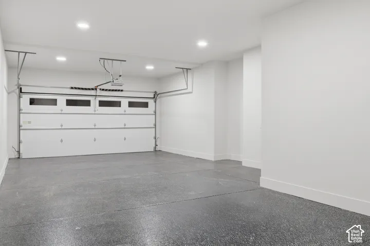 Attached garage with high-contrast epoxy flooring, smooth white walls, and recessed LED ceiling lighting