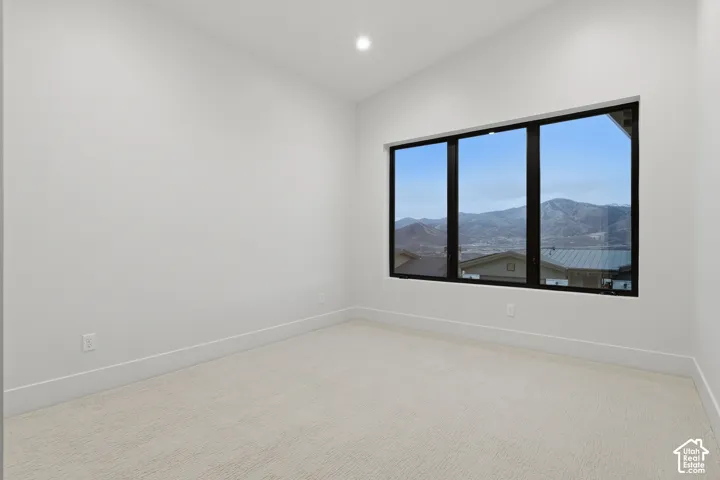 Vaulted ceilings, expansive windows with mountain scenery, and neutral carpeted flooring